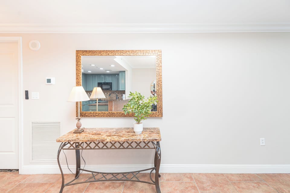 Step into your coastal-inspired retreat where elegant touches like a gold-framed mirror and marble console greet you, with your full kitchen just beyond the welcoming entryway.