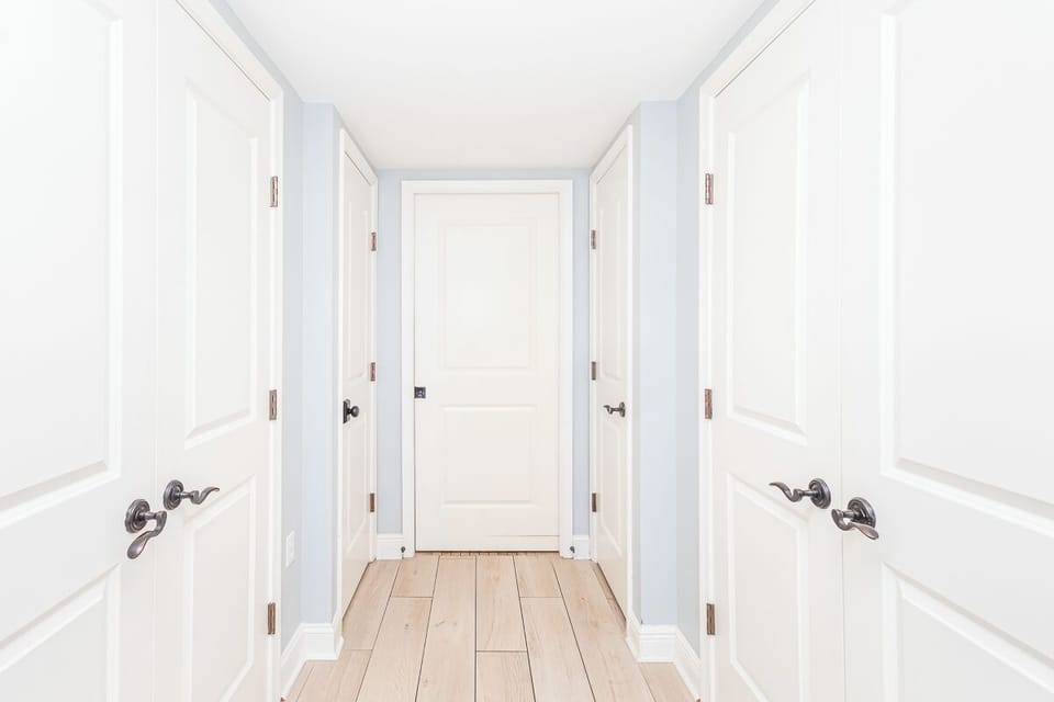Step into your private hallway featuring warm wood floors and coastal blue walls that create a serene, welcoming atmosphere.