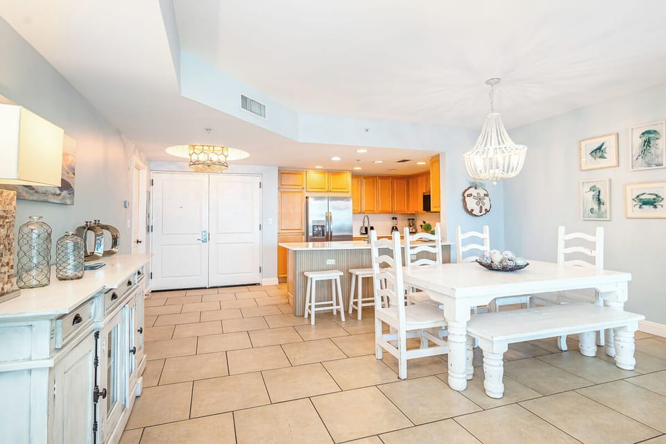 Your spacious open-plan kitchen and dining area features coastal charm with white furnishings and warm wood accents.