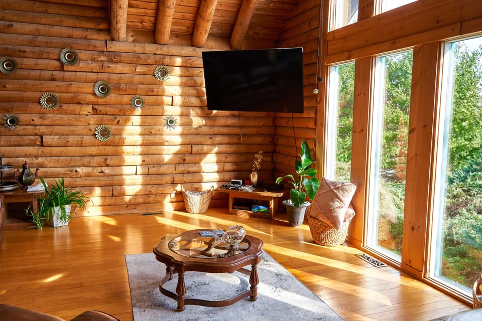 Cozy Spacious Living room showcases exposed log beams with Panoramic Windows