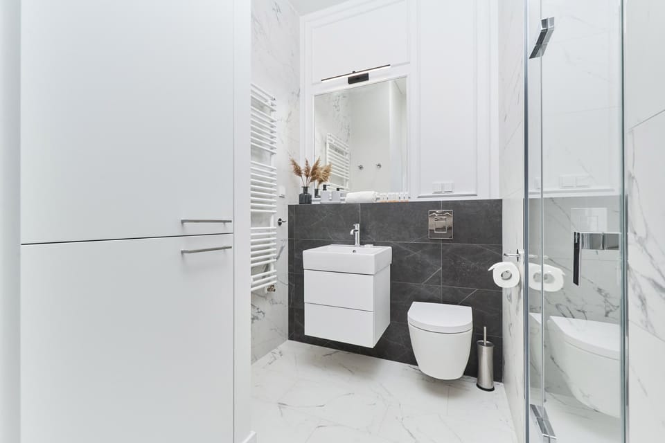 A bathroom with a white vanity, walk-in shower, and elegant marble finishes.
