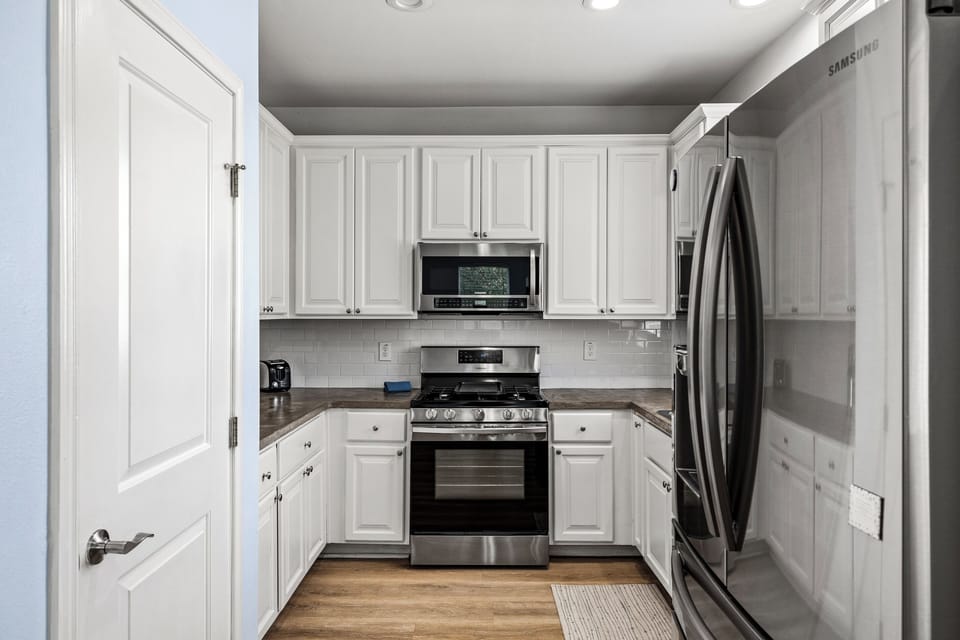 The fully equipped kitchen at Summer Bliss — white cabinets, stainless gas range, microwave, and a full-size fridge. Everything needed for group meals or quick beach snacks.