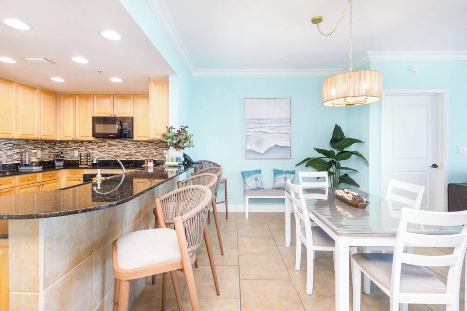 Your bright, coastal-inspired kitchen flows seamlessly into the dining area, where beach artwork and soothing blues create the perfect atmosphere for morning coffee.