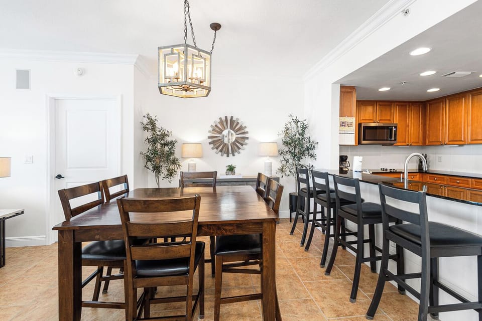 Gather around the warm wood dining table and breakfast bar, where morning coffee and shared meals feel effortlessly inviting in this sunlit, open-concept space connecting kitchen and living areas.
