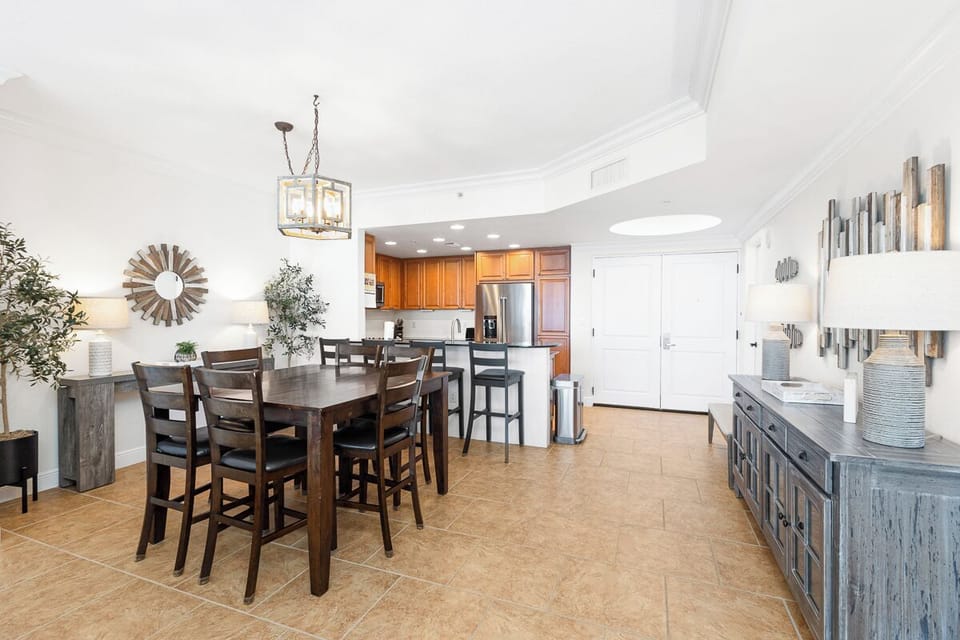 Gather around the elegant dining table where your group can share meals and laughter. The open layout connects to a fully equipped kitchen, making entertaining effortless and enjoyable.