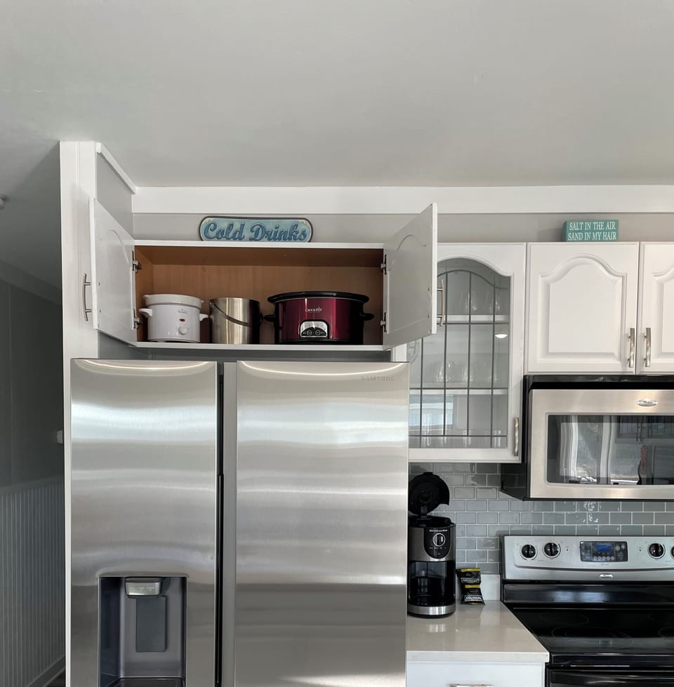 Stored above the fridge- a large and small crockpot for your use 