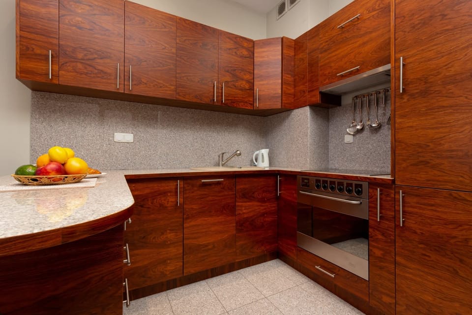A fully equipped kitchen with wooden cabinets, a modern stove, and a fruit bowl on the counter.