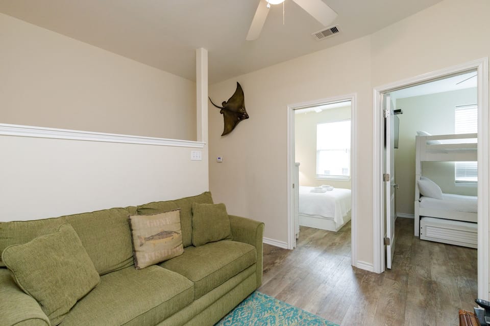 Unwind in your spacious living area with plush olive seating, connecting you to peaceful bedrooms through elegant archways.
