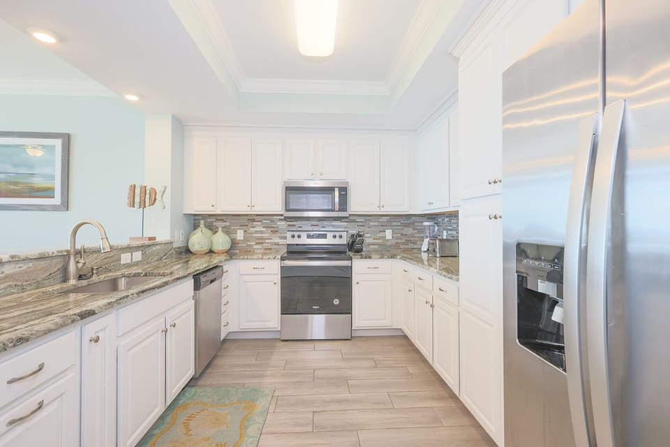 Prepare meals in this kitchen with elegant cabinetry, stainless appliances, and stylish backsplash