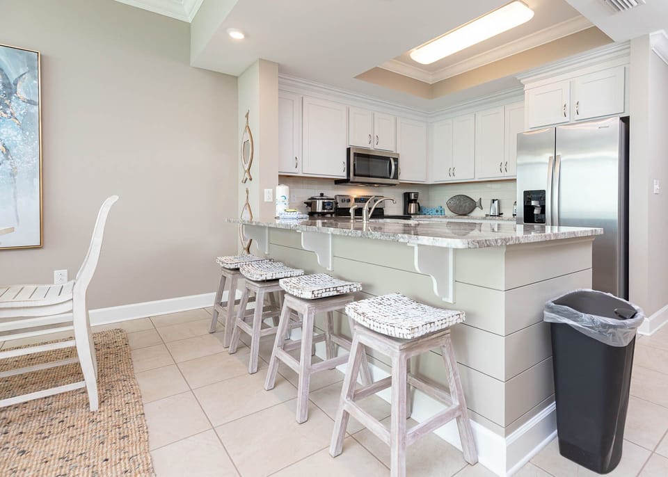 Savor your mornings at the sleek breakfast bar, brewing coffee while soaking in the inviting coastal ambiance