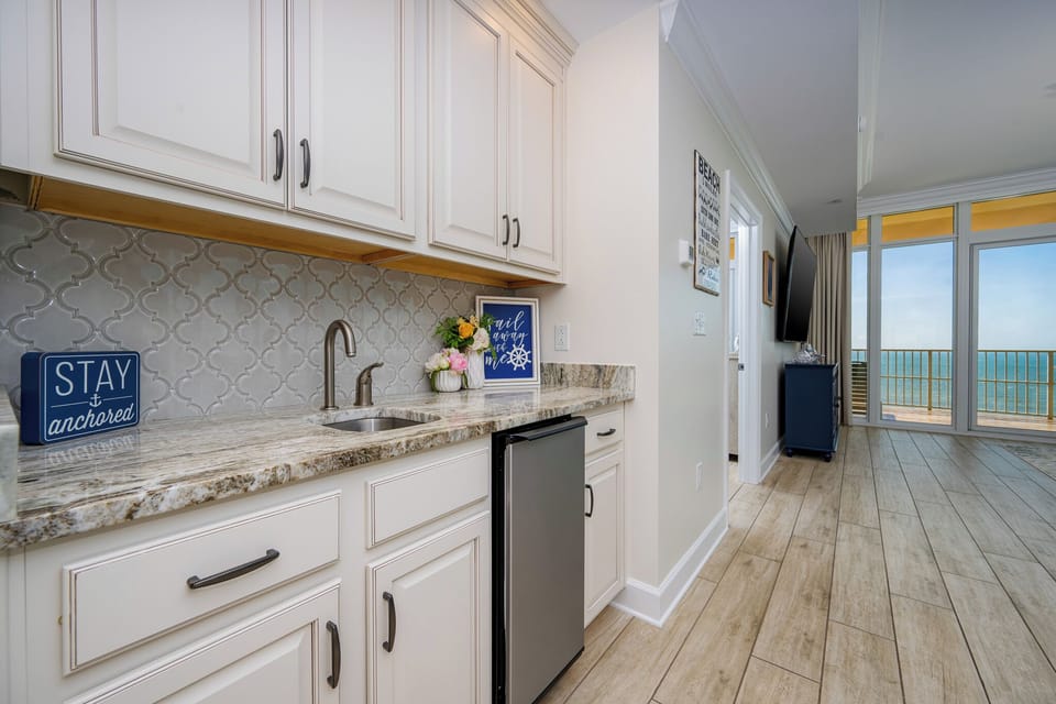 Sip refreshing drinks at the sleek wet bar while enjoying the view of the beach from your cozy retreat