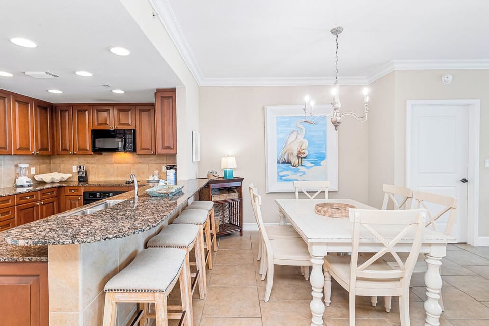 Your open kitchen flows into an elegant dining area where you'll enjoy meals under a beautiful chandelier and coastal artwork.