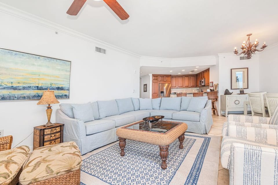 Relax in your spacious living area with soft blue seating and coastal charm, where open-concept design flows seamlessly into your fully-equipped kitchen and dining space.