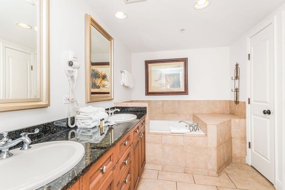 Unwind in your private spa-like bathroom, featuring a deep soaking tub, dual sinks with elegant granite counters, and soft lighting throughout.