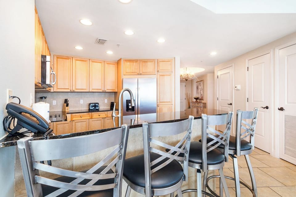 Gather around the spacious breakfast bar in this fully-equipped kitchen, where warm wood cabinetry, modern appliances, and plenty of counter space make meal prep a breeze for your group.