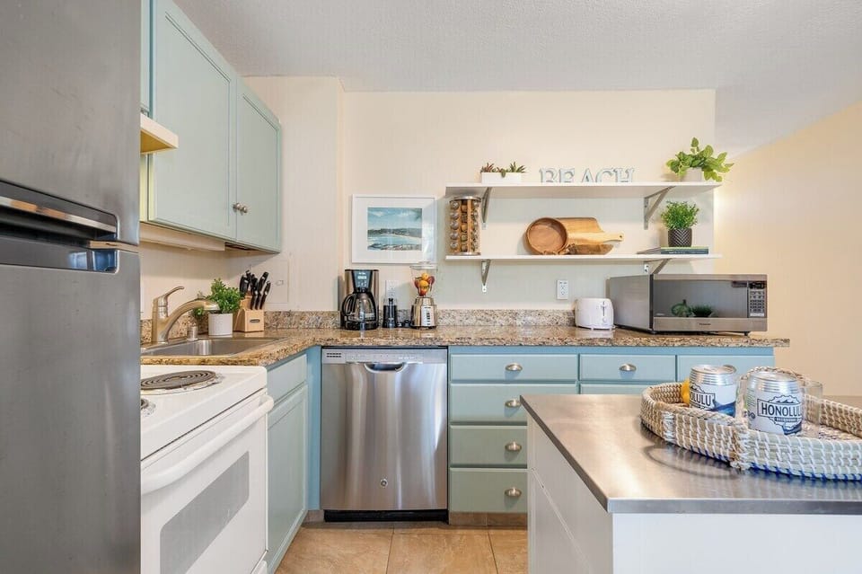 Fully equipped kitchenette with stainless steel appliances, custom teal cabinetry, and all the essentials for home-cooked meals.
