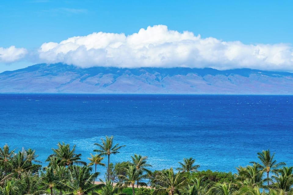 Gaze across the channel to Molokai from Honua Kai, where vibrant blues and lush palms frame an iconic island view.