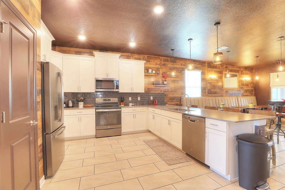 The open-concept kitchen features a Starbucks coffee bar and is fully equipped with dishes, pots, and pans. It includes a complete suite of stainless steel appliances: dishwasher, refrigerator, microwave, stove, oven, air fryer, instant pot and toast