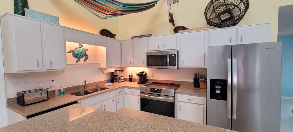 Kitchen with newer flat surface stove, microwave and refrig with water/ice