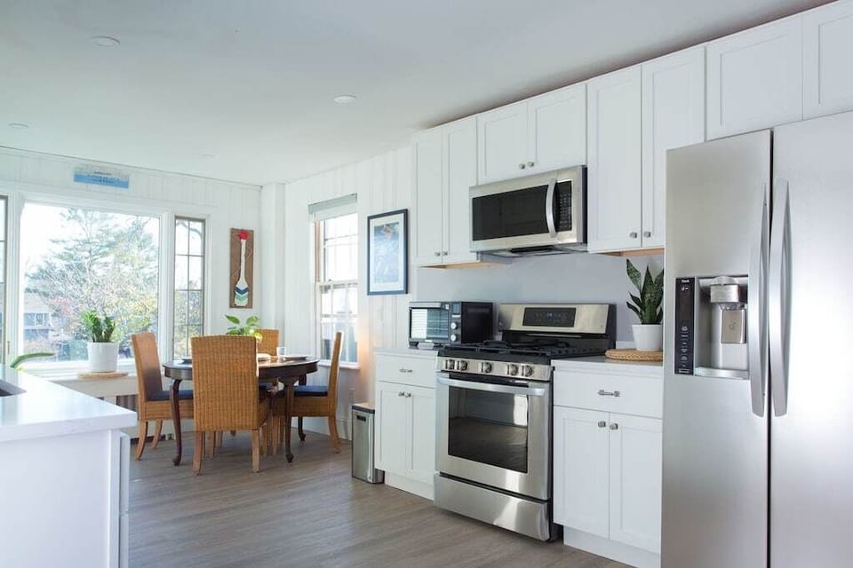 Kitchen: Bright and modern space with stainless steel appliances and sunlit dining area.