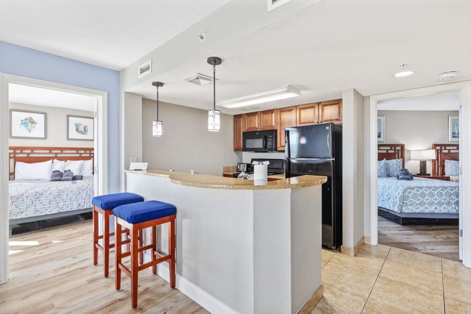 This condo features a thoughtful, open layout with a well-equipped kitchen and a convenient counter for casual meals or catching up while making a snack.