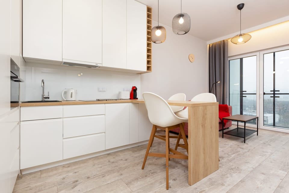 Compact and practical kitchen design with integrated appliances and a wooden breakfast table for casual meals.