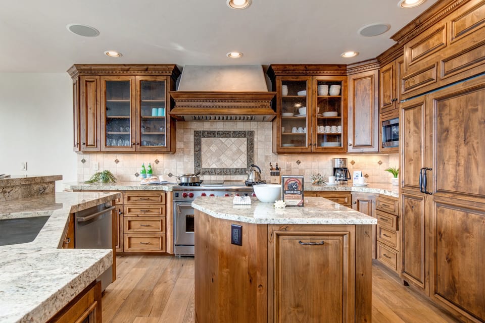 Fully equipped kitchen with Wolf appliances, Sub-Zero fridge, double ovens, stone countertops, island, and bar seating for 5.