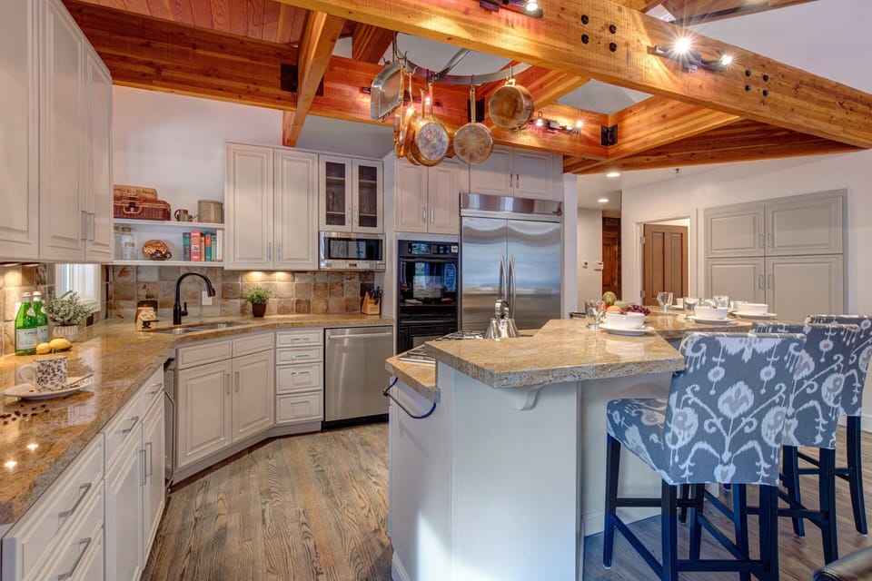Fully Equipped Kitchen with stainless steel appliances, stone countertops, wine fridge, and bar seating for 4