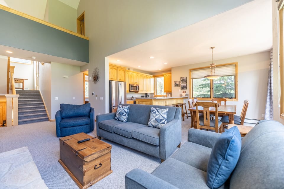 Sink into plush blue seating in your open-concept living space, where soaring ceilings and warm wood accents create the perfect gathering spot for your mountain getaway.