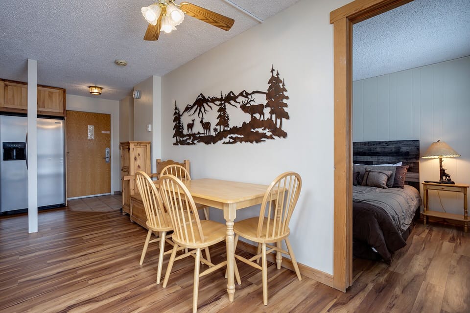 Your cozy mountain retreat features warm wood details, rustic artwork, and an open layout connecting dining and sleeping areas perfectly.