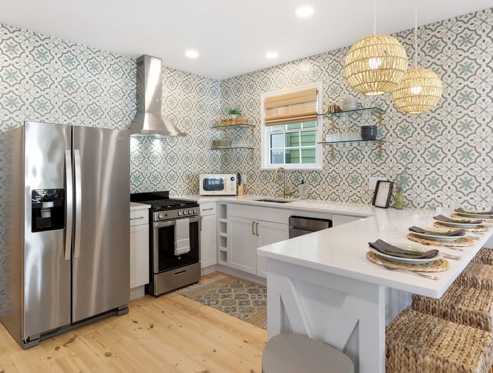 Bright and inviting kitchen with beautiful green tiling and open shelving. 