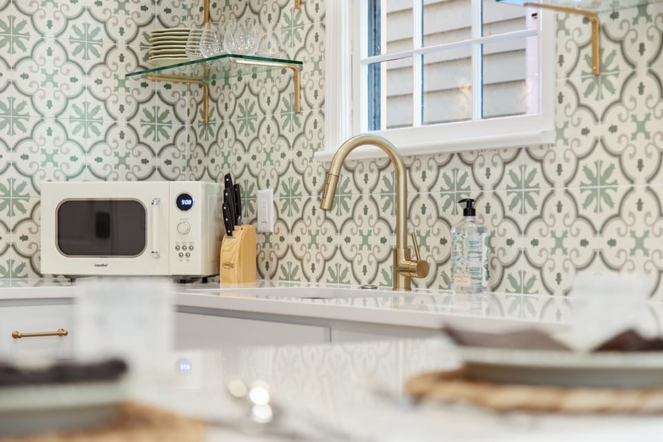 Bright and inviting kitchen with beautiful green tiling and open shelving. 