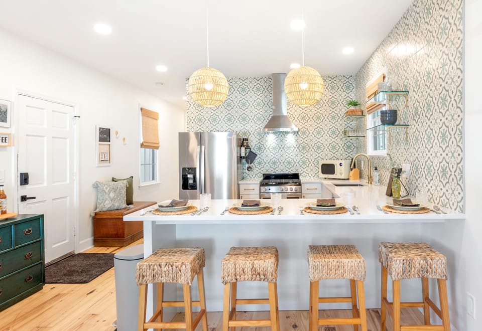 Bright and inviting kitchen with beautiful green tiling and open shelving. 
