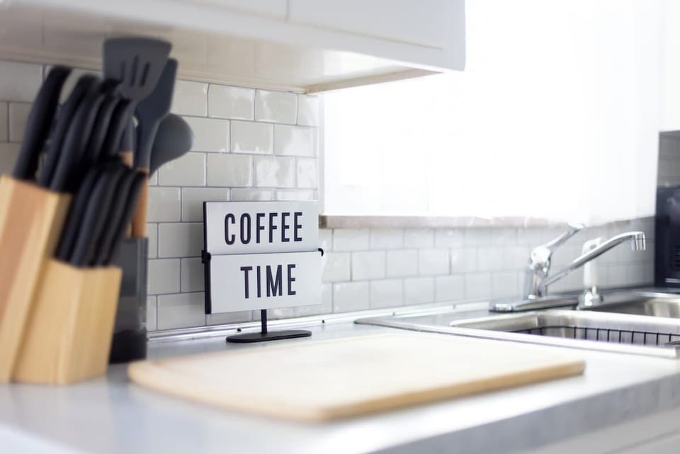 - Kitchen decor with coffee time sign for daily perk   - Airbnb stay offering thoughtful guest touches   - Stylish counter detail with practical kitchen tools  
