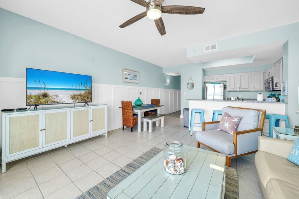 Your coastal living space blends relaxation with modern comfort—soft blues, breezy fans, and beach vibes create the perfect vacation retreat.