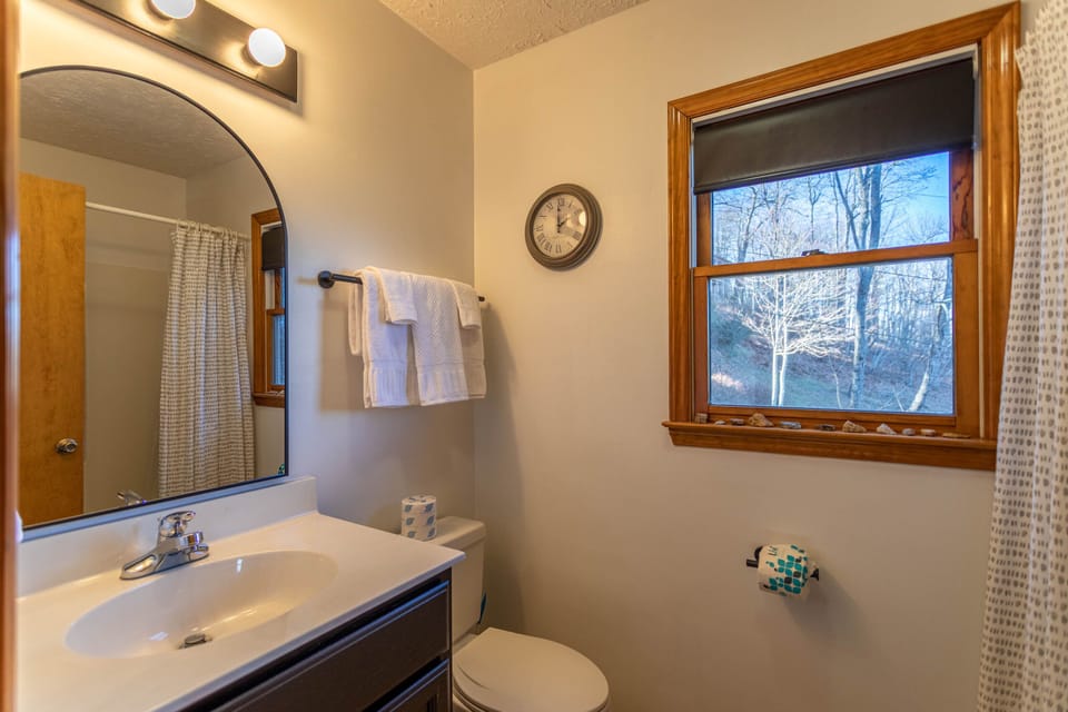 A bright, tidy bath with a wooded view right outside the window. Fresh towels and cozy details ready for your arrival.