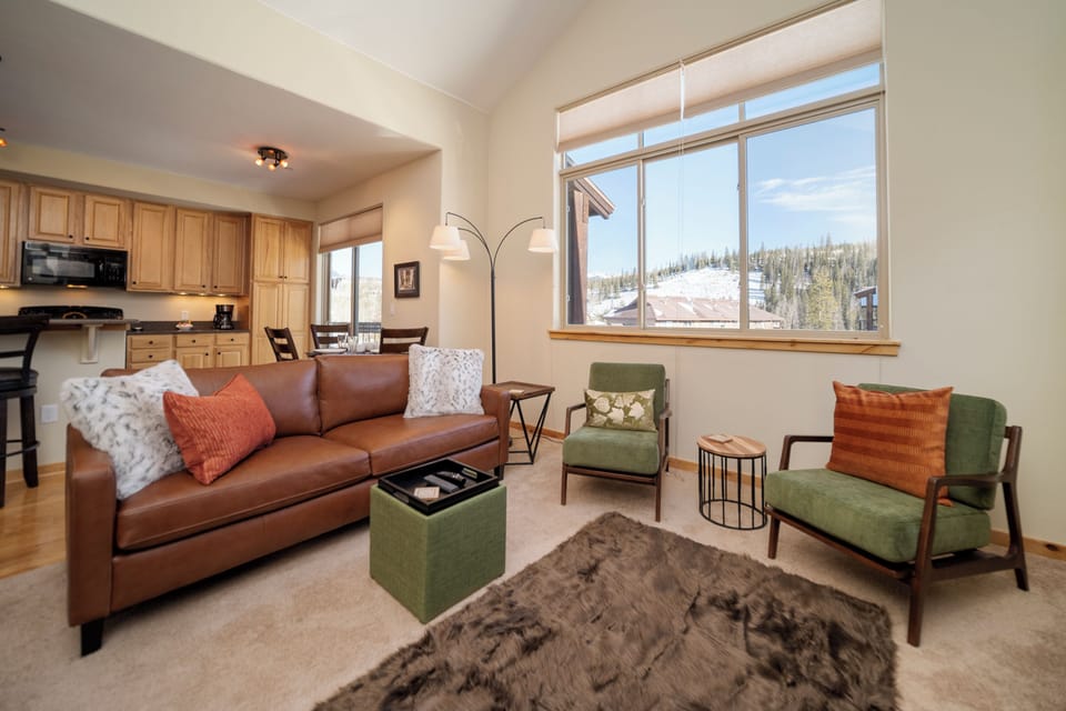 Relax in your cozy living room with plush leather seating and stunning mountain views through expansive windows.