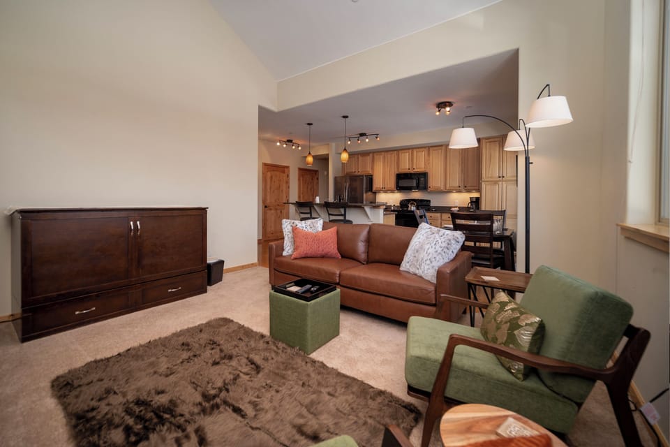 Sink into plush leather seating surrounded by warm wood tones and modern lighting in your stylish open-concept living space.