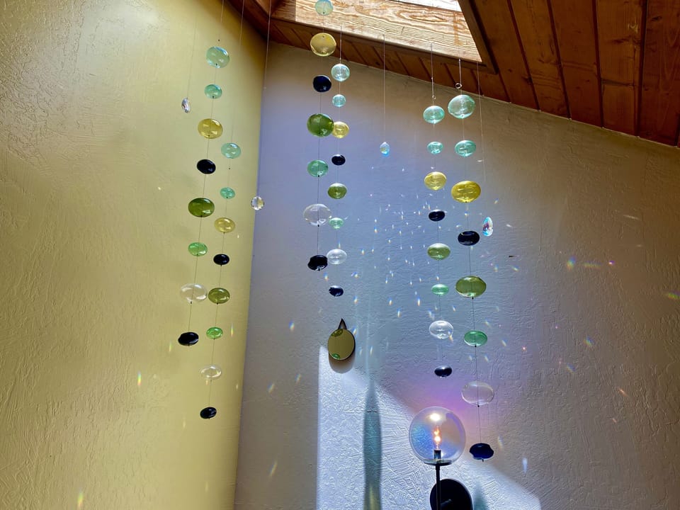 Natural light chandelier hanging from skylight on vaulted ceiling.