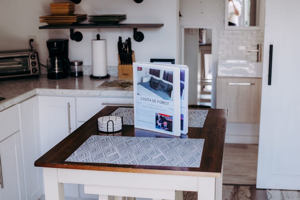 This modern kitchenette features a white island with a dark wood top, set with geometric placemats.