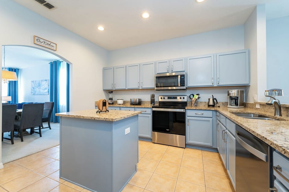 Open kitchen with granite countertops, center island, and stainless steel appliances.