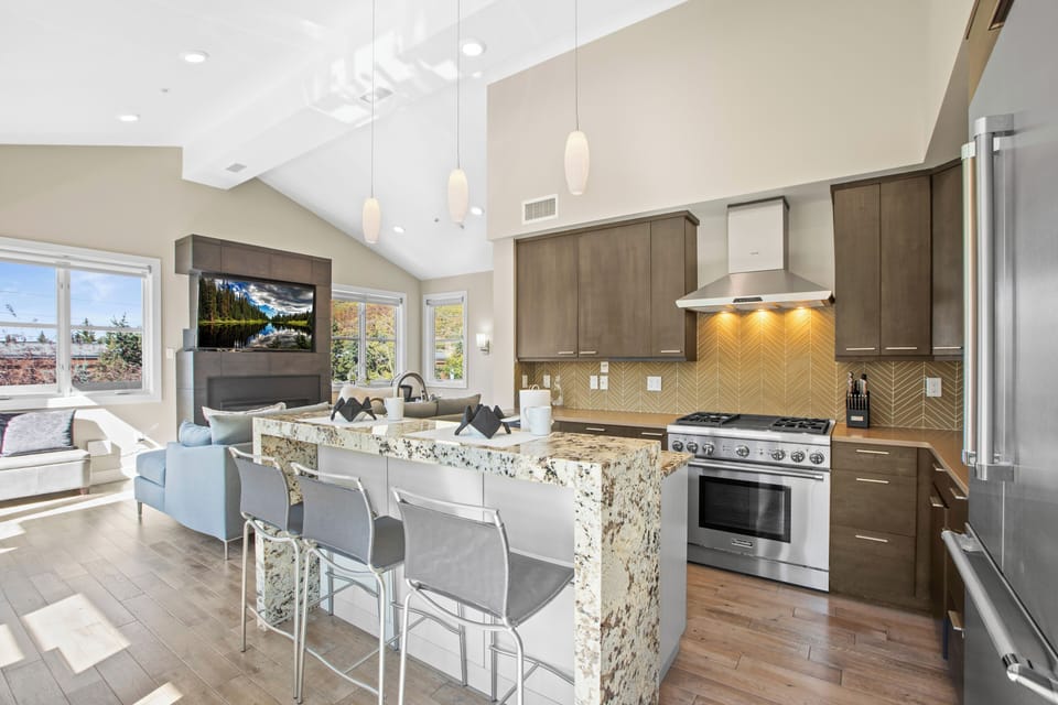 Open concept kitchen with waterfall island and stainless steel appliances.