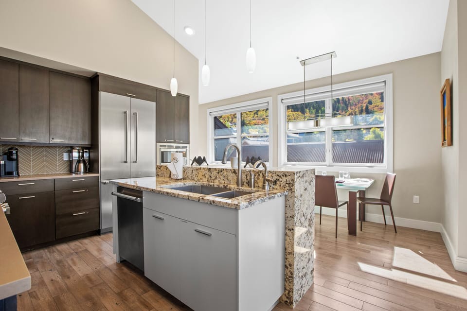 Open concept kitchen with waterfall island and stainless steel appliances.
