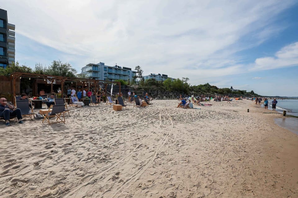 A sandy beach bustling with life, surrounded by clear blue skies and inviting waters.
