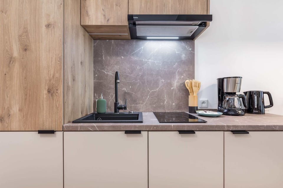 A minimalist kitchen setup with natural wood finishes, a black stovetop, and smart storage solutions.
