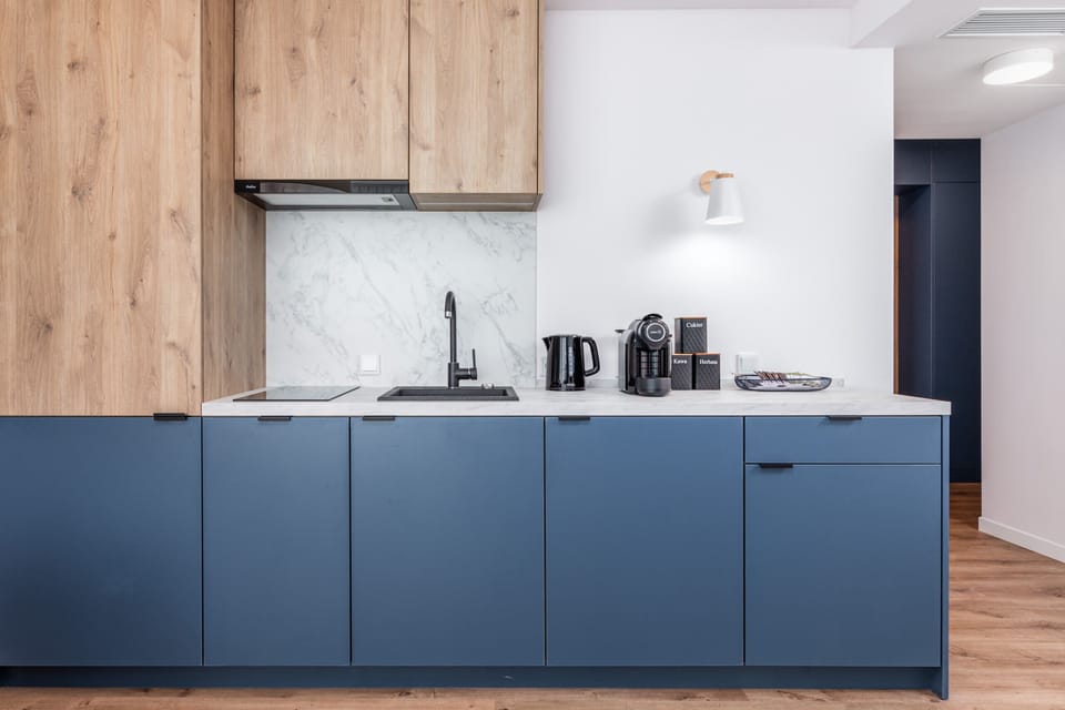 A small kitchenette with wooden finishes and essential appliances, like a coffee maker and kettle.