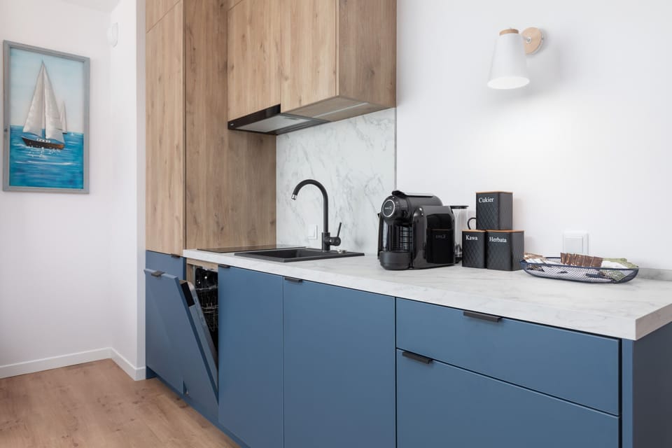 A small kitchenette with wooden cabinets and blue drawers, equipped with basic appliances like a kettle and toaster.
