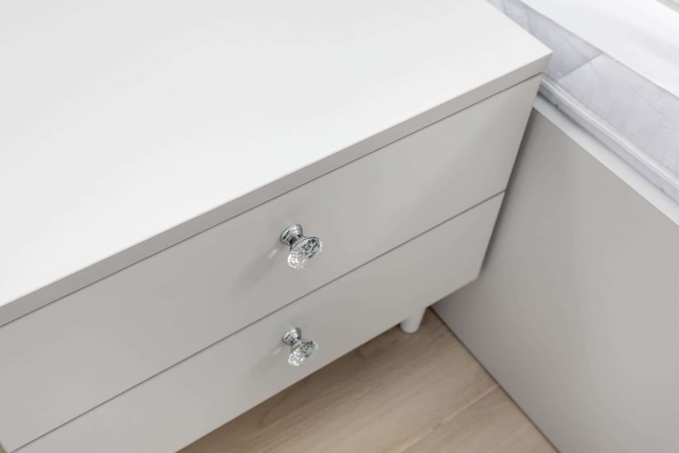 A close-up view of a white drawer with shiny metallic handles, emphasizing minimalist design.