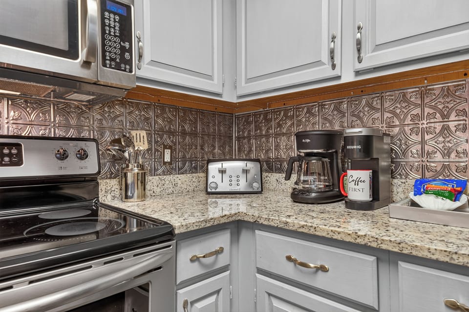 Your fully equipped kitchen features stainless steel appliances, granite countertops, and a decorative tin backsplash—perfect for brewing morning coffee or preparing meals during your stay.