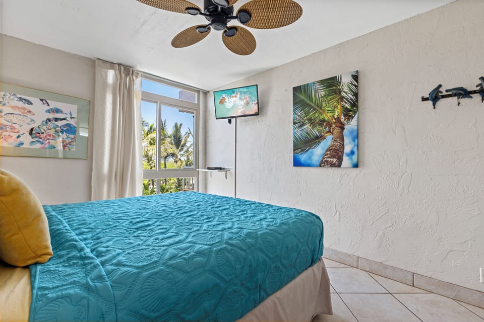 Sink into your plush bed beneath a tropical-style ceiling fan, with palms swaying outside your window. Coastal artwork and a mounted TV make this your breezy island retreat.